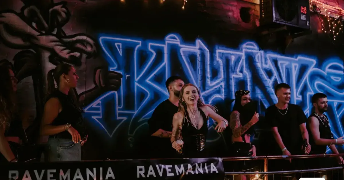 Mehrere feiernde Menschen hinter dem RAVEMANIA-DJ-Pult beim Open Air Day & Night Rave 2026 in Düsseldorf